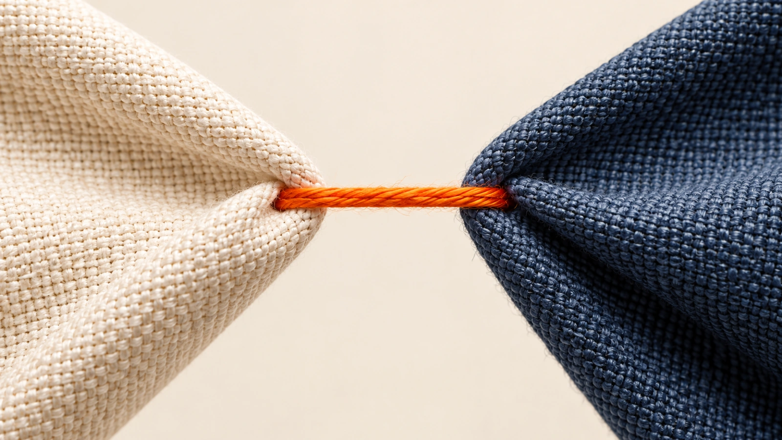 Orange thread joining two woven fabrics, illustrating relevant connections.